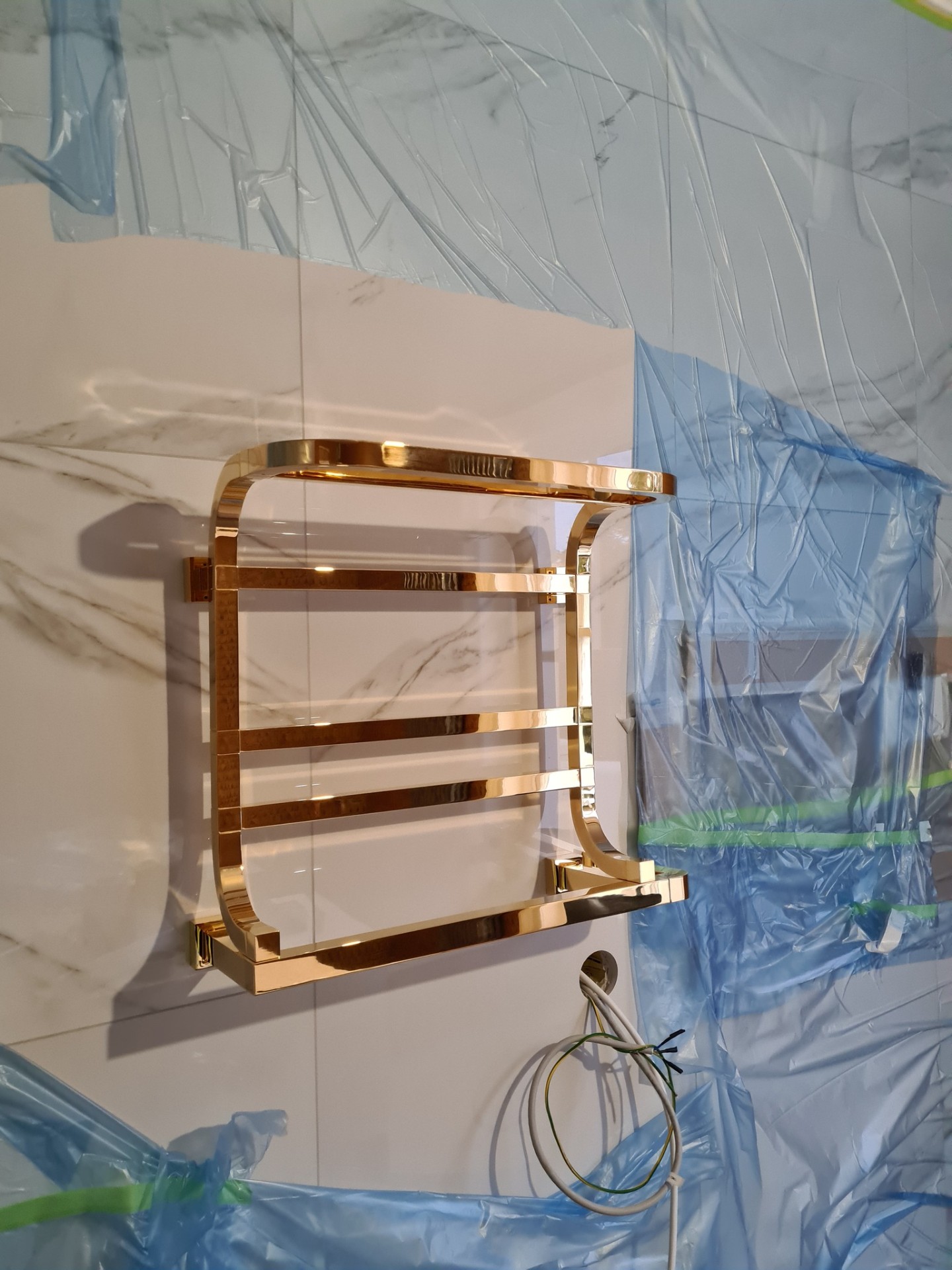 Gold heated towel rail installed on marble bathroom wall