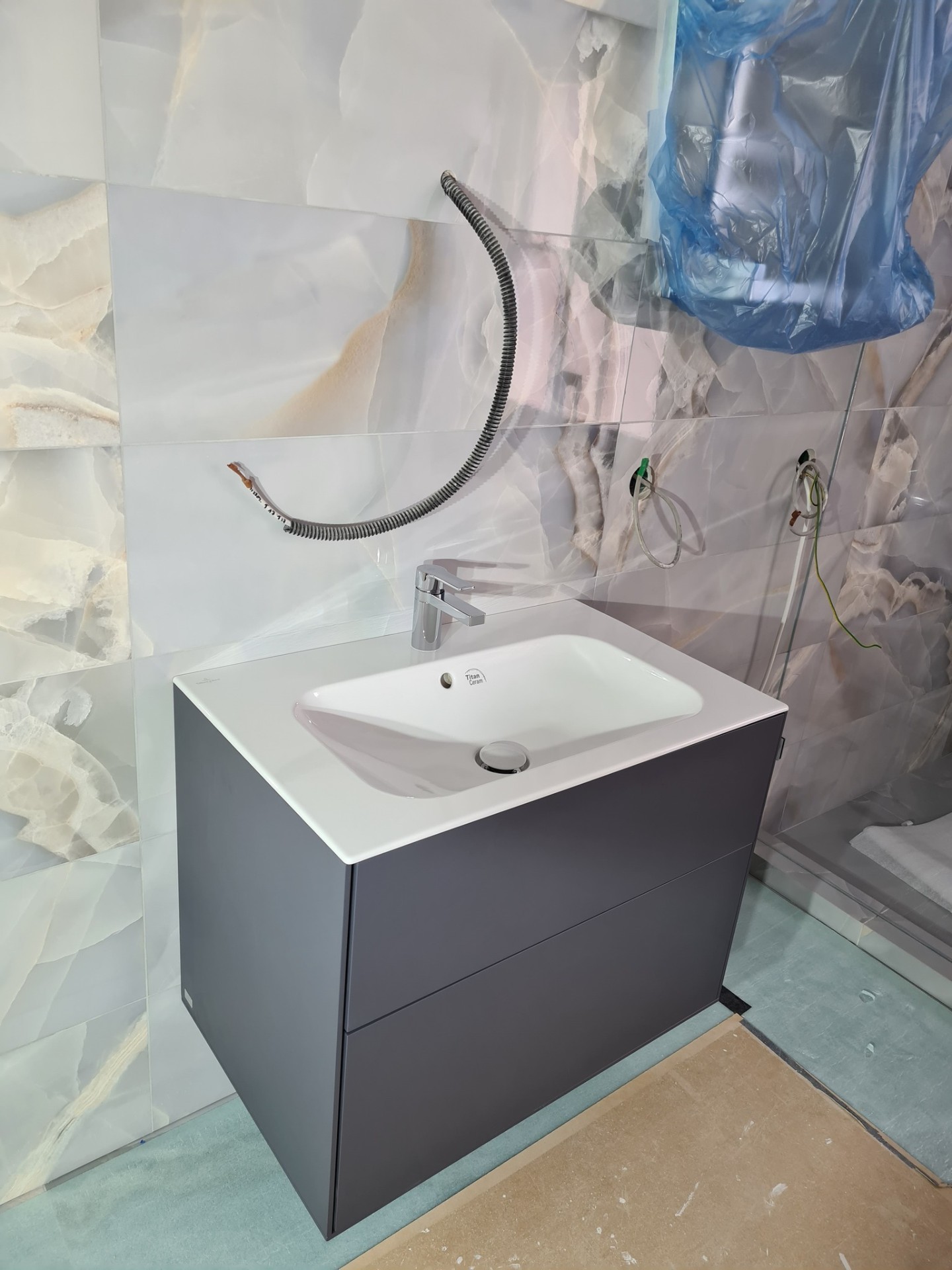 Grey wall-hung vanity unit with integrated basin on marble-effect tiles