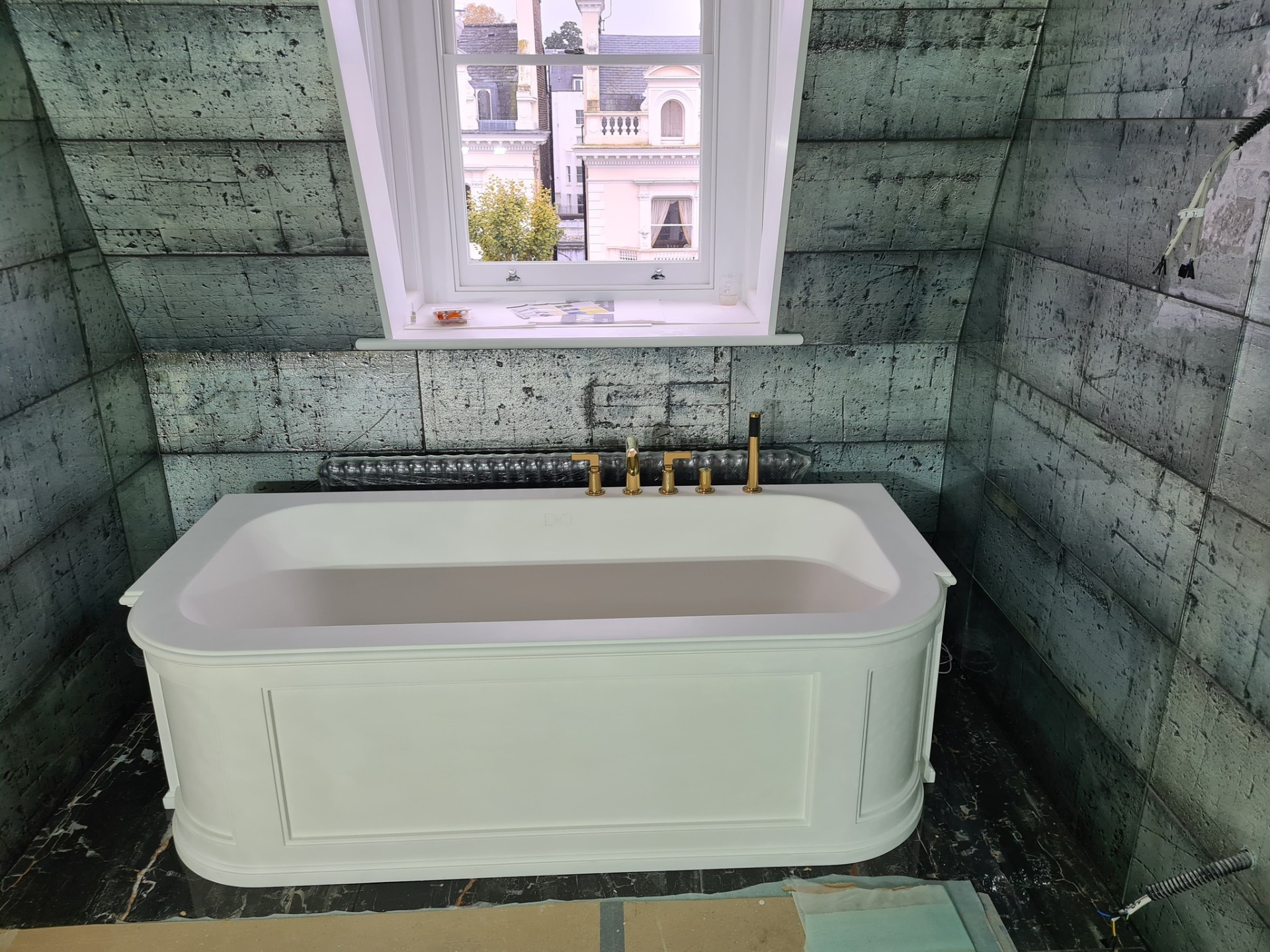 Luxury bathtub with gold deck-mounted taps and green textured wall tiles