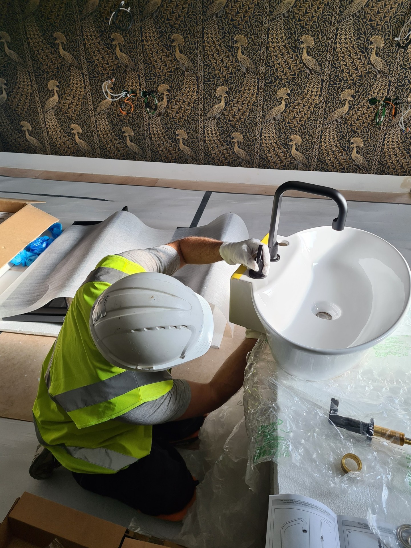 Engineer installing black basin mixer tap on vessel basin