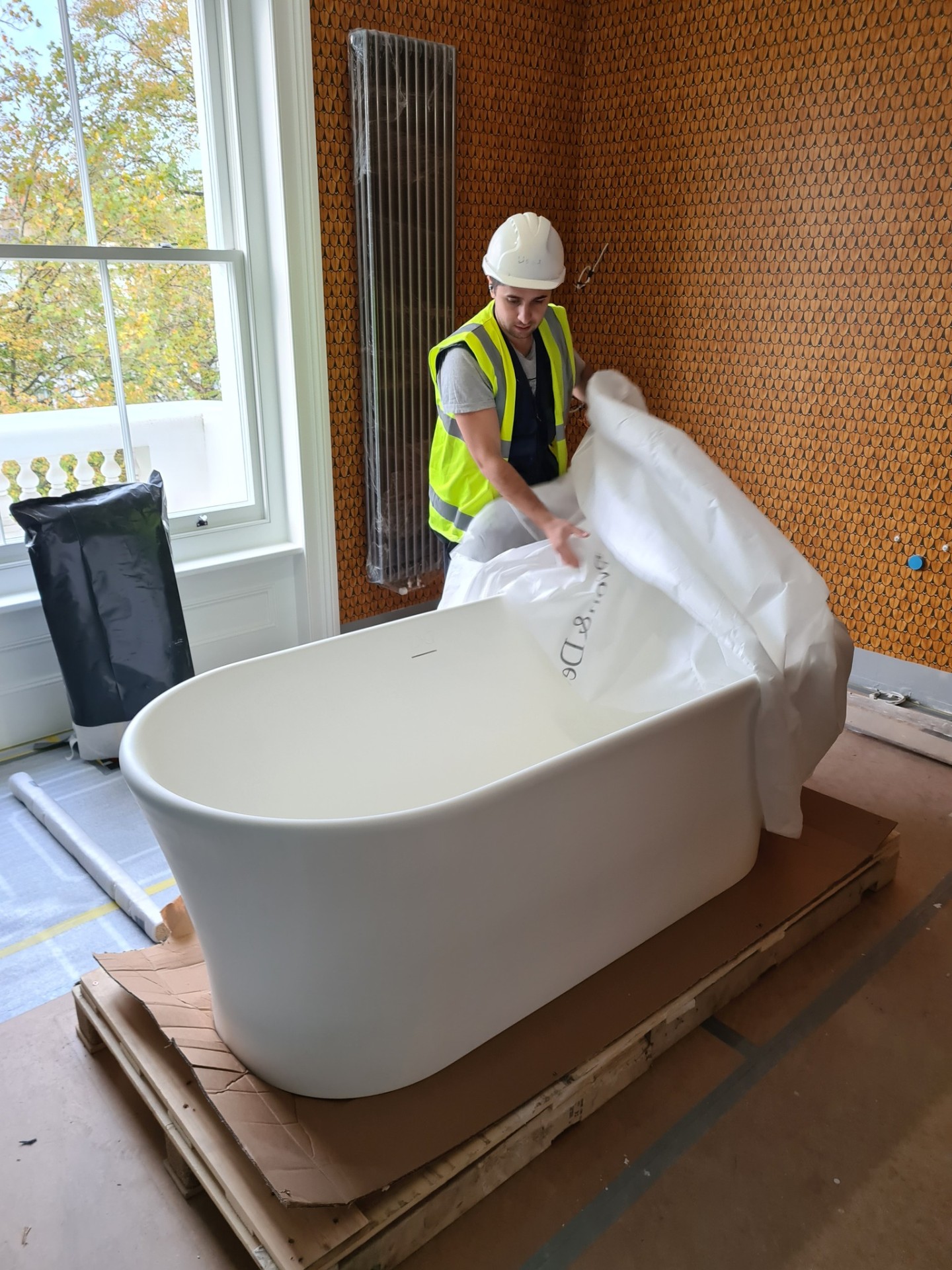 Engineer carefully unpacking freestanding bath for bathroom installation